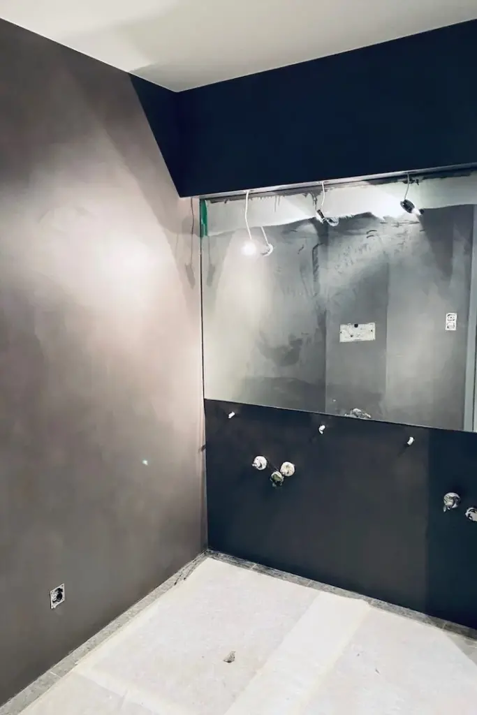Badezimmer im Rohbau mit Glasabtrennung und vorbereiteten Anschlüssen