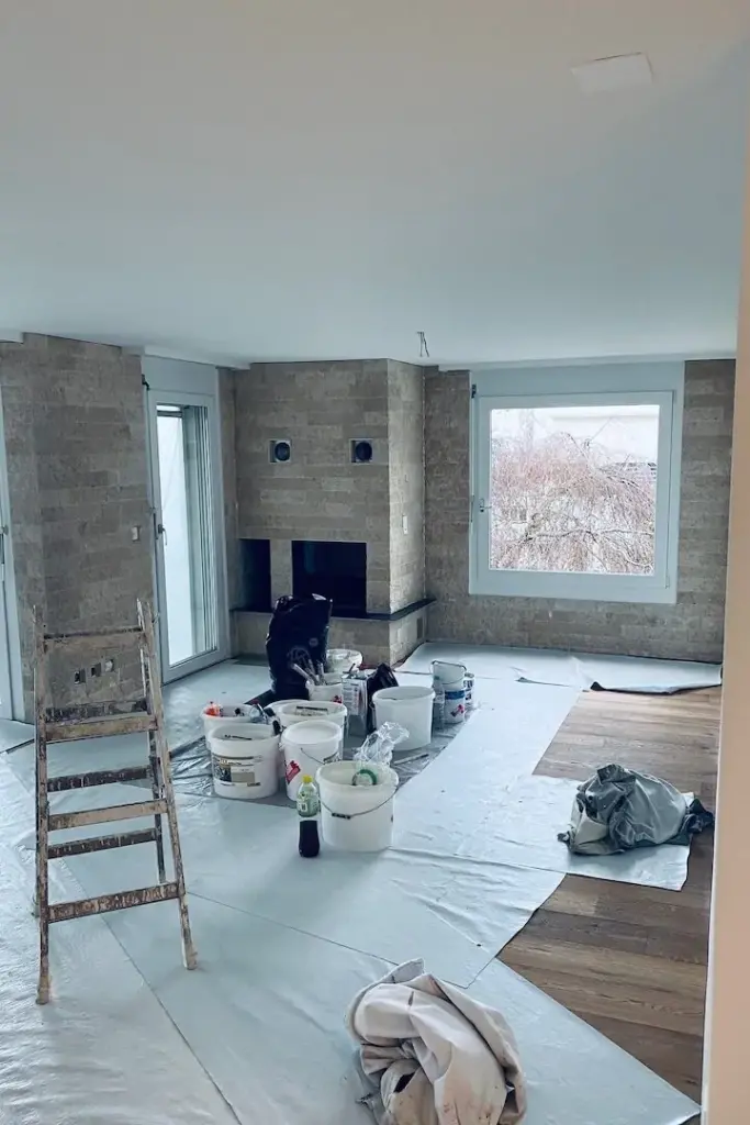 Wohnraum im Umbau mit Backsteinwand, Abdeckfolie und Malerutensilien