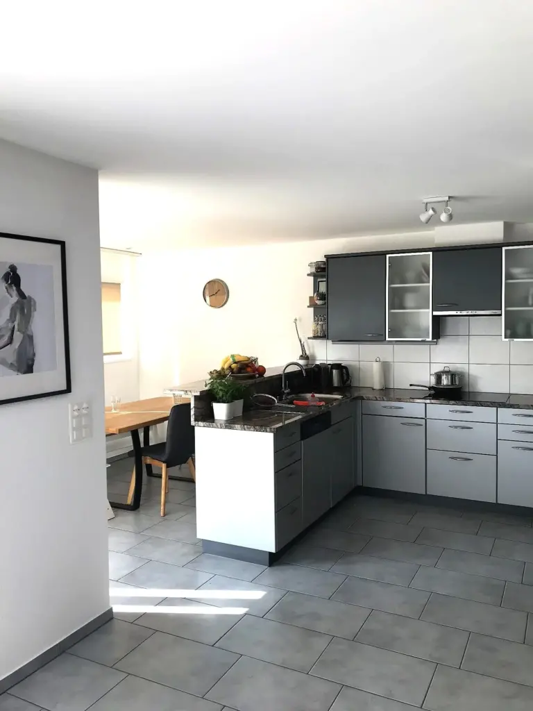 Küche mit grauen Fronten, Essplatz und hellem Fliesenboden