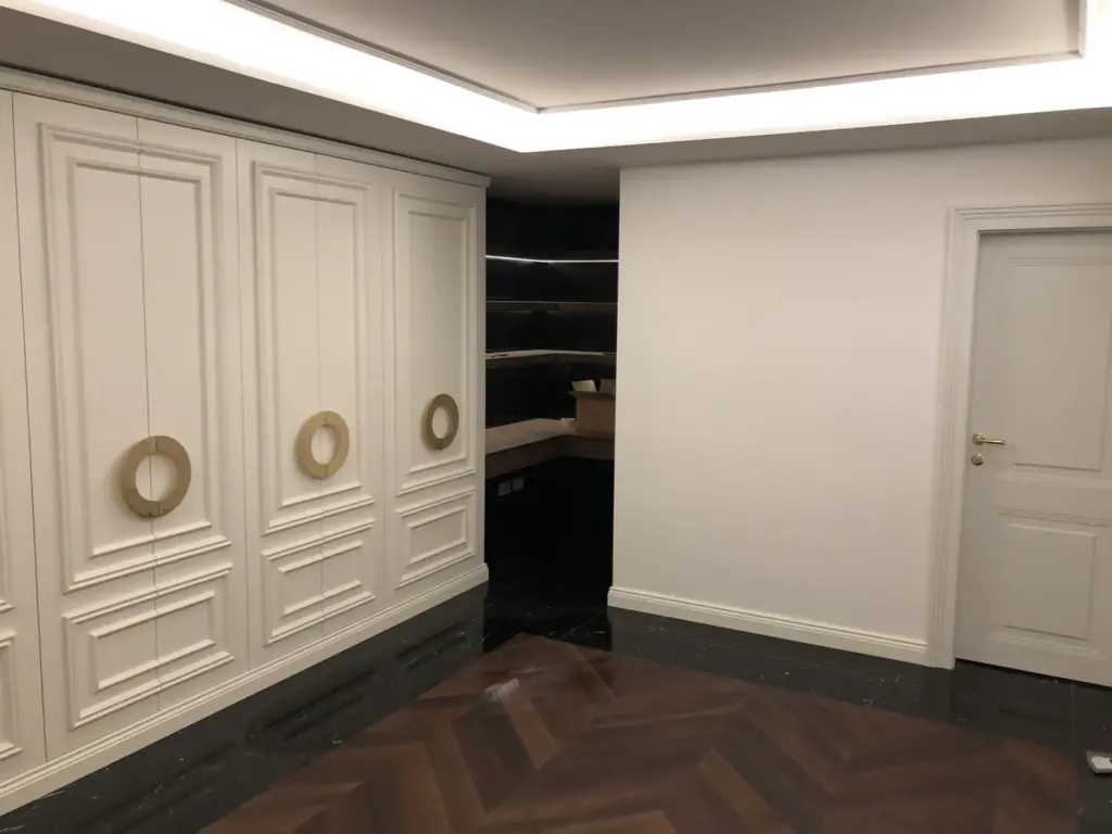 Raum mit weisser Kassettenwand, Durchgang zur Regalnische und Fischgrätparkett