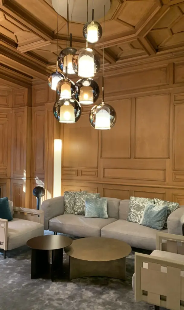 Lounge mit Holzvertäfelung, Ecksofa und Leuchtentraube aus Glaskörpern