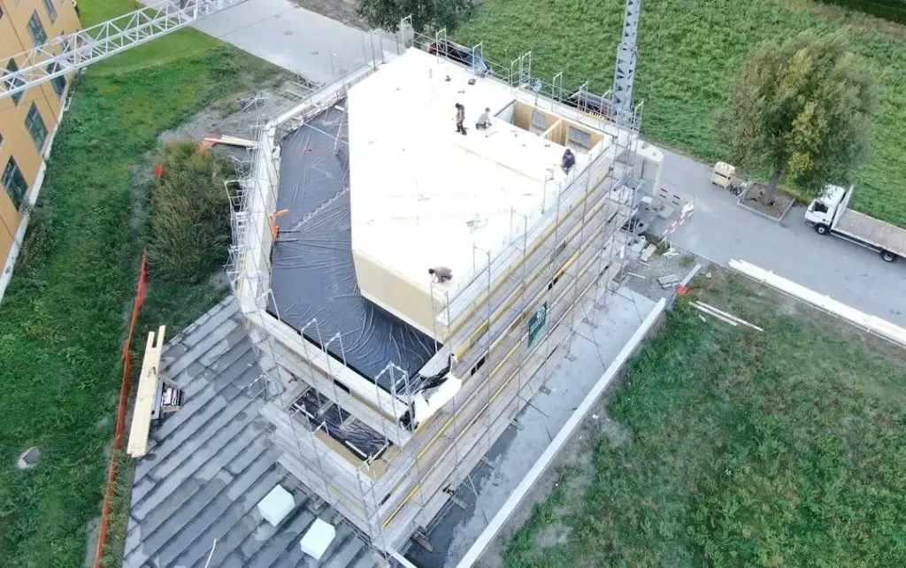 Rohbau mit gedämmtem Flachdach aus der Luft, umgeben von Gerüst