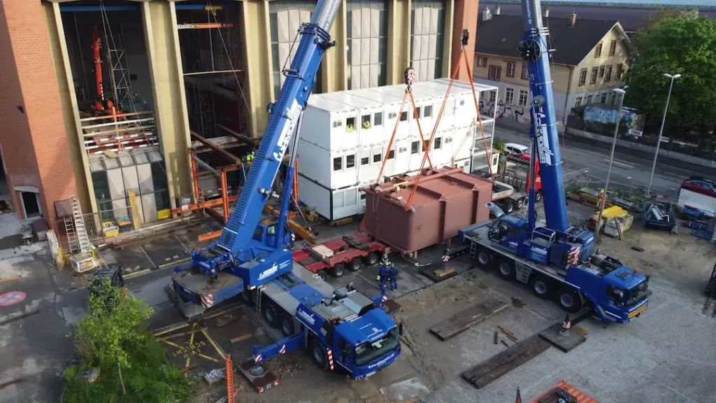 Zwei Mobilkräne heben ein Anlagenmodul auf die Baustelle des Heizwerks
