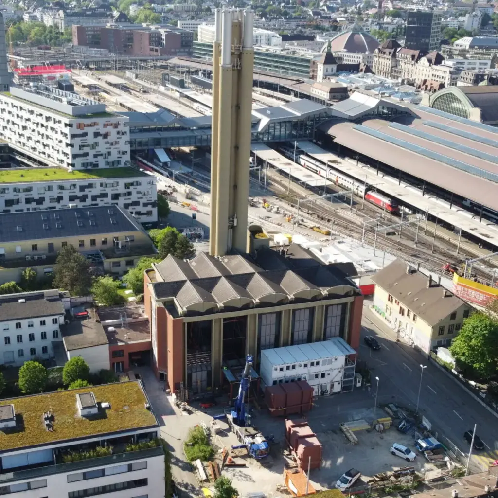 Luftaufnahme des IWB-Heizwerks mit Kamin neben dem Gleisfeld des Bahnhofs Basel