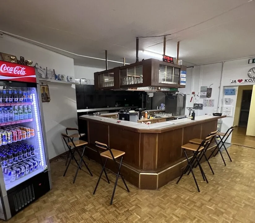 Alte Clubhaus-Bar mit Holztheke, Barhockern und Getränkekühlschrank vor dem Umbau