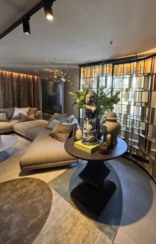 Wohnbereich mit bodenlangen Vorhängen, Sofa und rundem Tisch mit Blumenvase