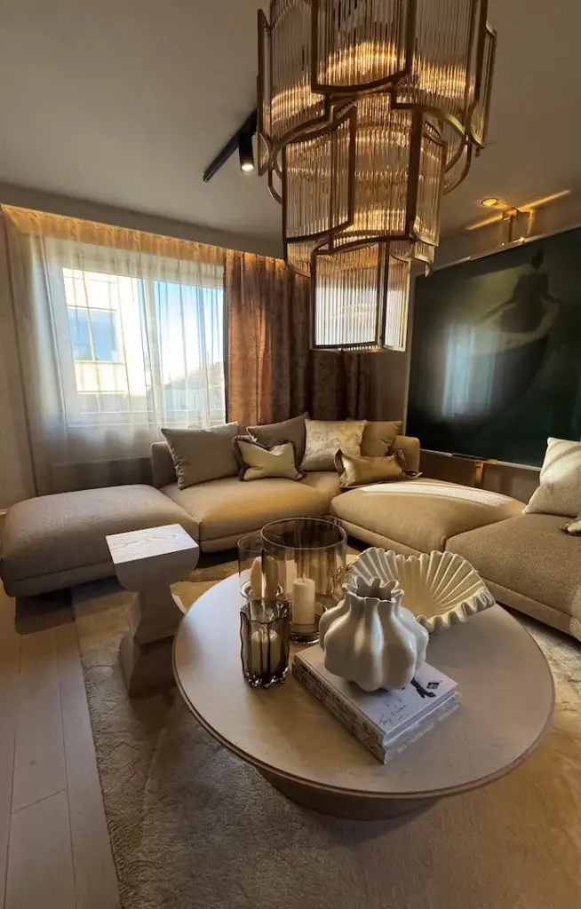 Wohnzimmer der Suite mit goldenem Deckenleuchter, Sofalandschaft und rundem Couchtisch