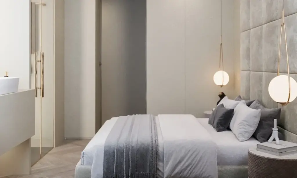Schlafzimmer mit gepolstertem Kopfteil, Pendelleuchten und Ankleide