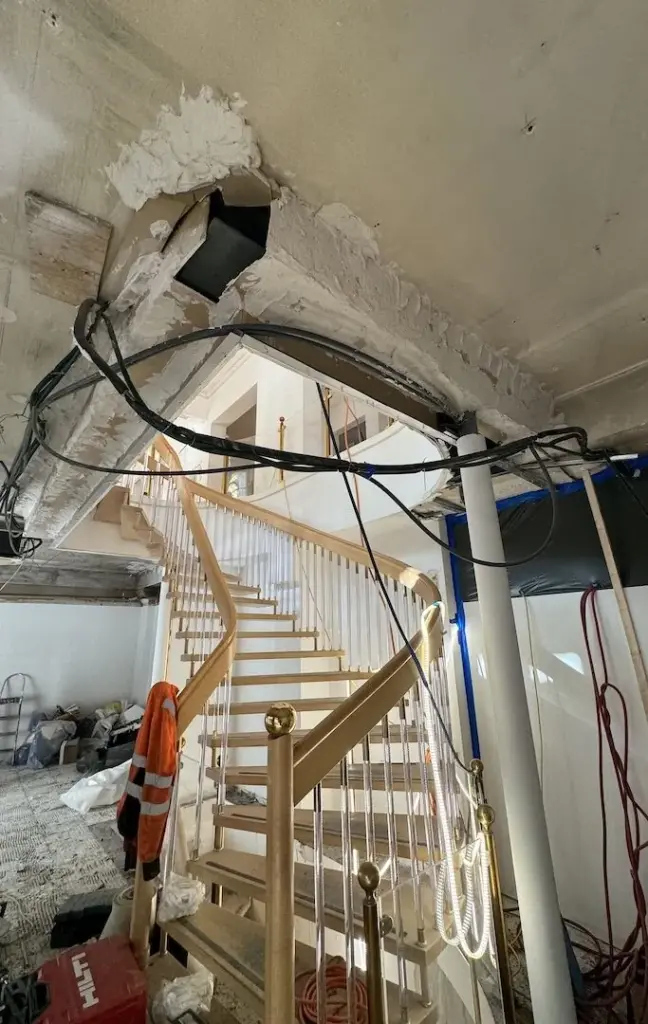 Treppenhaus während der Entkernung mit freigelegter Decke und Leitungen