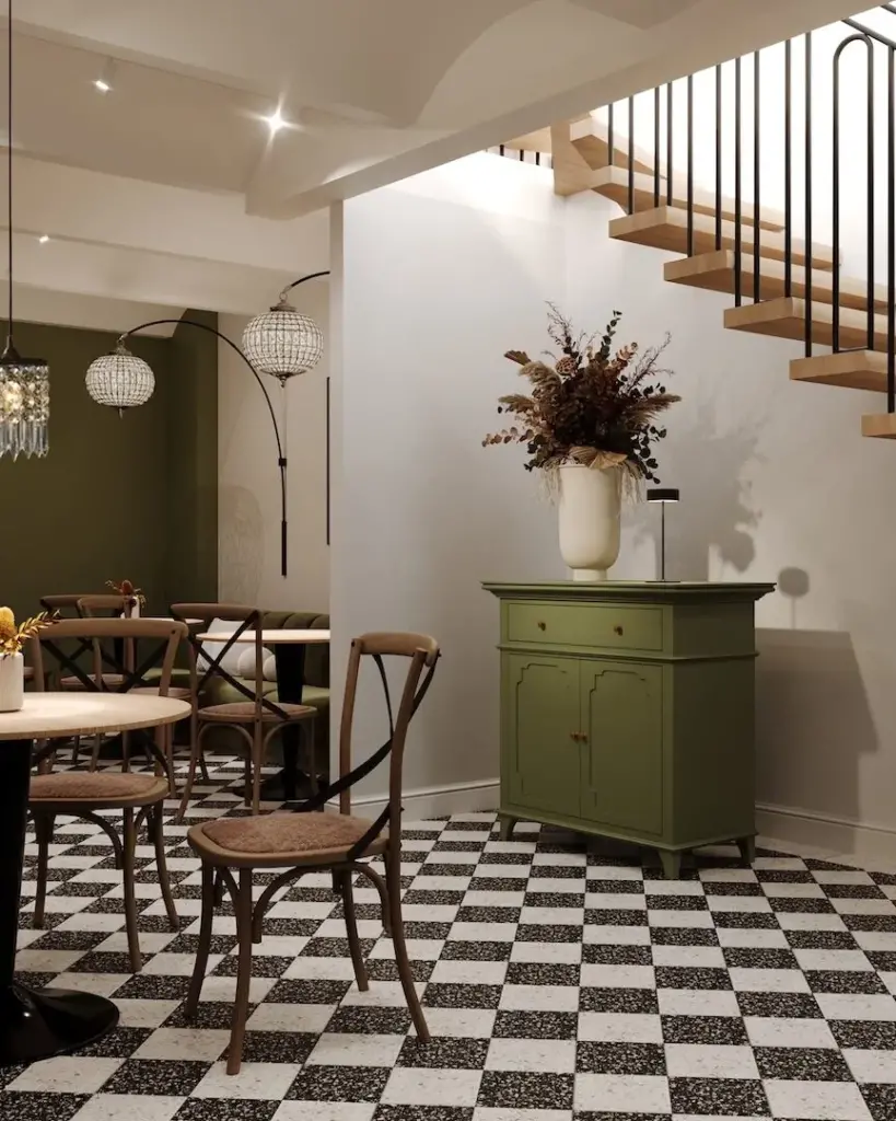 Unteres Gastlokal mit Treppe, grüner Kommode und olivfarbener Wand