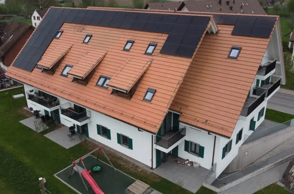 Dachlandschaft des Mehrfamilienhauses mit Solarmodulen und Dachfenstern