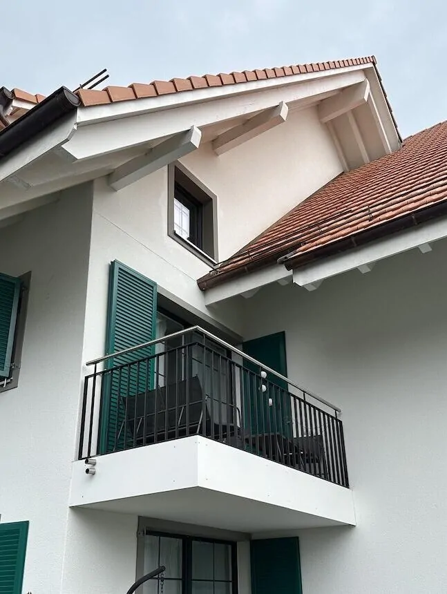 Weiss verputzte Fassade mit grünen Fensterläden, Balkon und Dachgaube